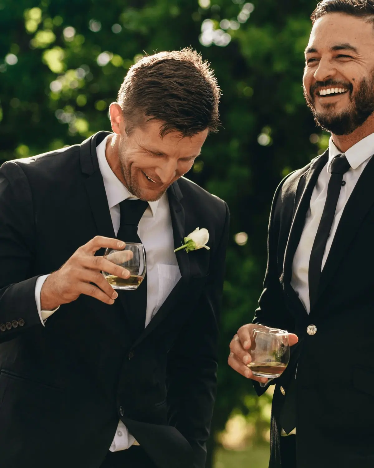 Groomsmen laughing together in custom black wedding suits